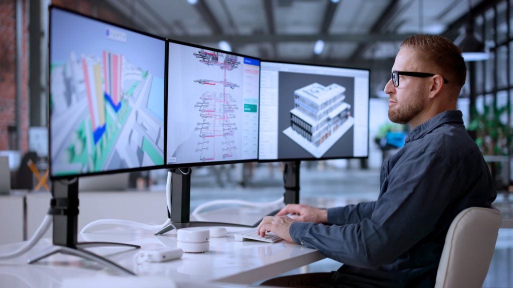 Engineers reviewing technical designs on multiple computer screens