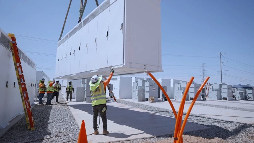 Construction workers guiding electrical equipment into position during installation