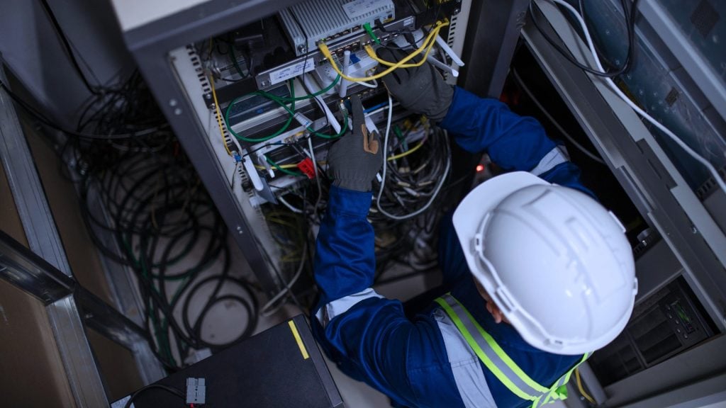 Technician installing network cabling in a server rack